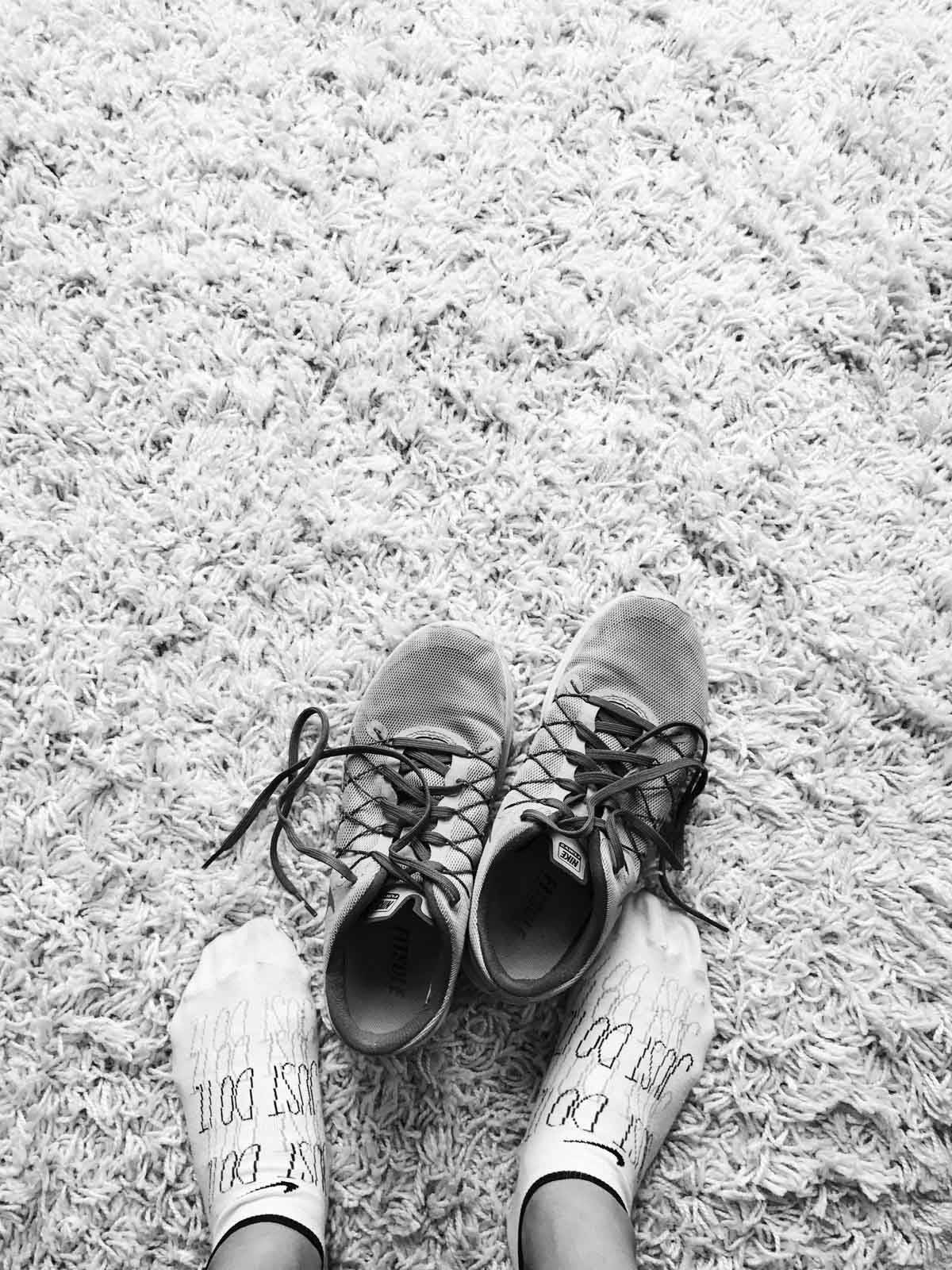 Feet outside of shoes on a carpet.
