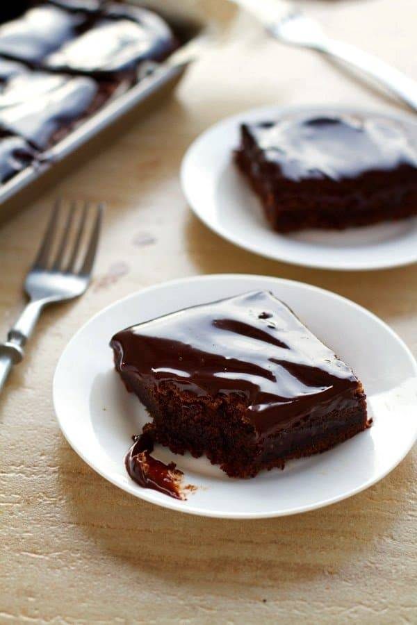 Fudgy chocolate cake bars on white plates.