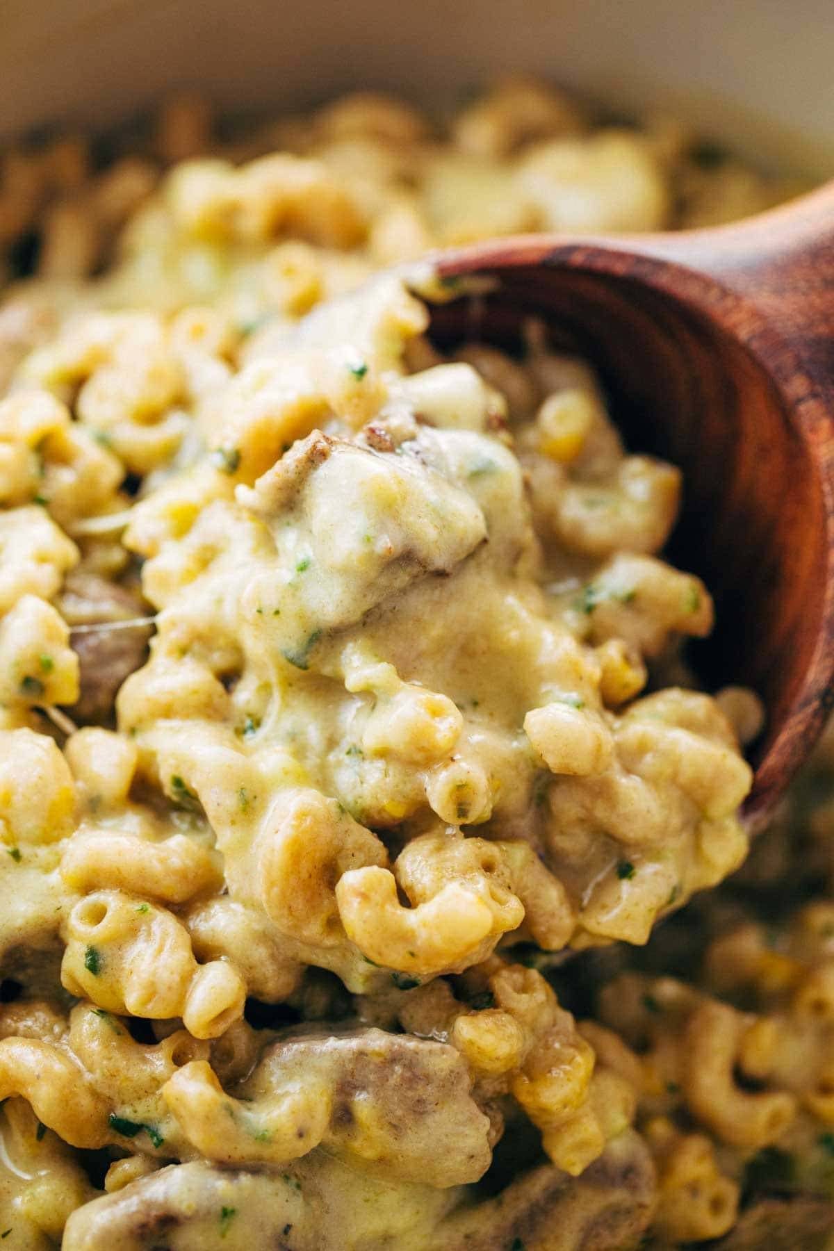 Steak and Cheddar Mac and Cheese with a wooden spoon.