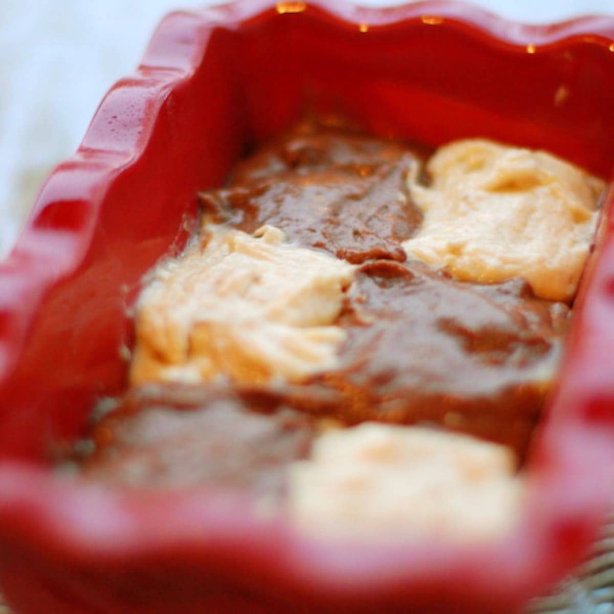 Chocolate checkered banana bread dough in a red baking dish.
